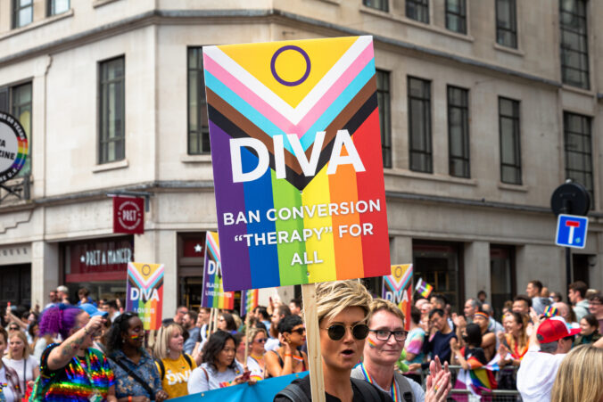 London, UK - 2 July, 2022: color image depicting people holding signs against conversion therapy at the 50th London Gay Pride parade in the city centre. People are dressed in colorful outfits, and the rainbow flag - the symbol of the LGBTQ community - is prevalent. Piccadilly is thronged with people at this celebratory event. Room for copy space.