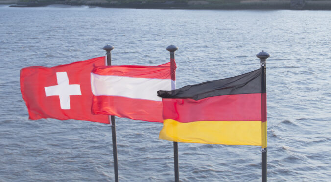 A Swiss, Austrian and German flag on a river's edge